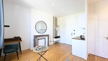 Een moderne woonkamer met een open haard, een ronde spiegel, een klein rond tafeltje en een bank.