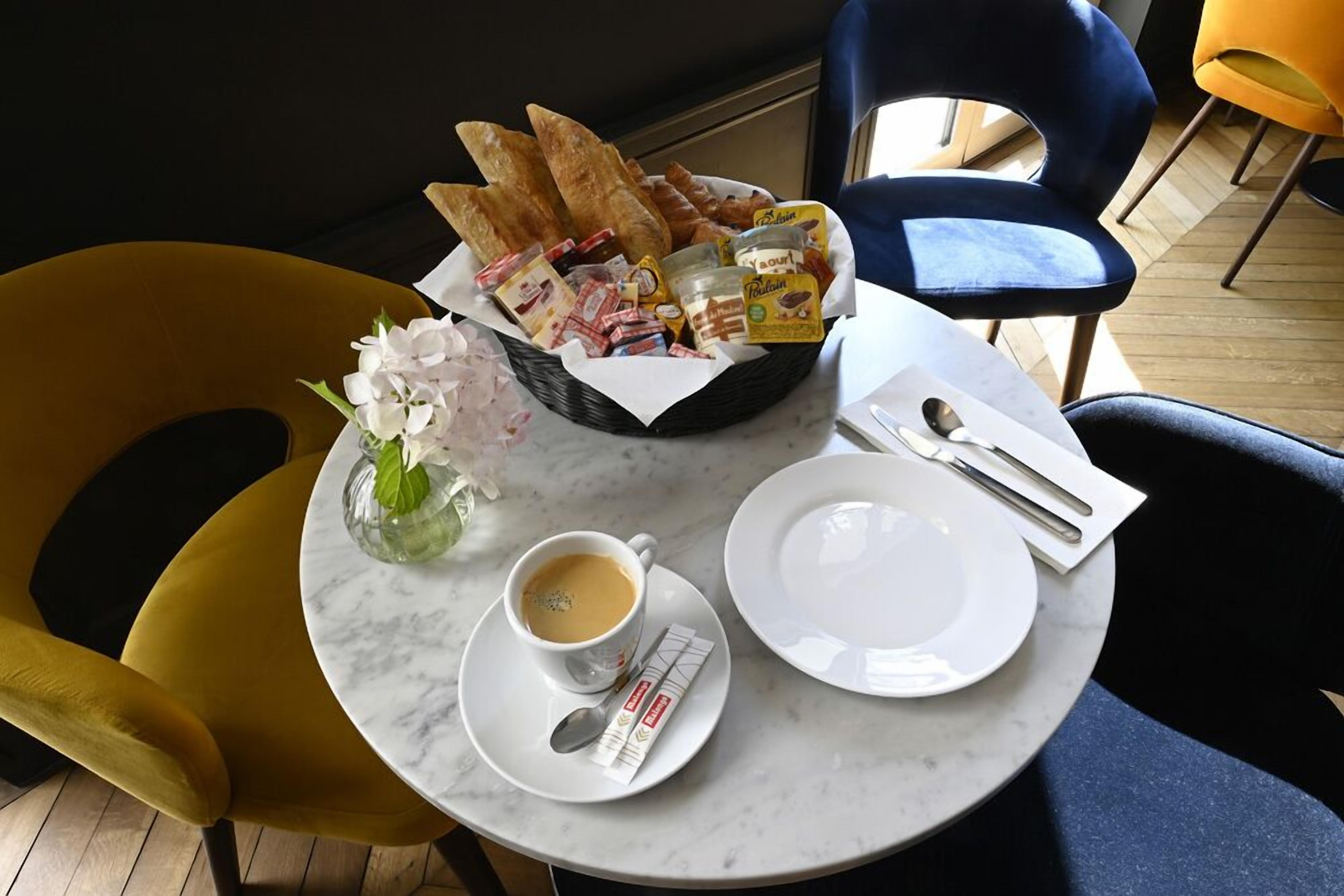 Ein Esstisch mit einem Brotkorb, einem Teller, einer Kaffeetasse und einer Vase mit Blumen.