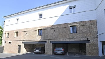 A two-story building with a white upper section and a brick lower section. There are two garages with cars parked inside.