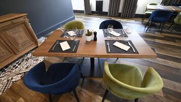 A dining area with a wooden table set for two, two chairs, a small potted plant, and a black vase.