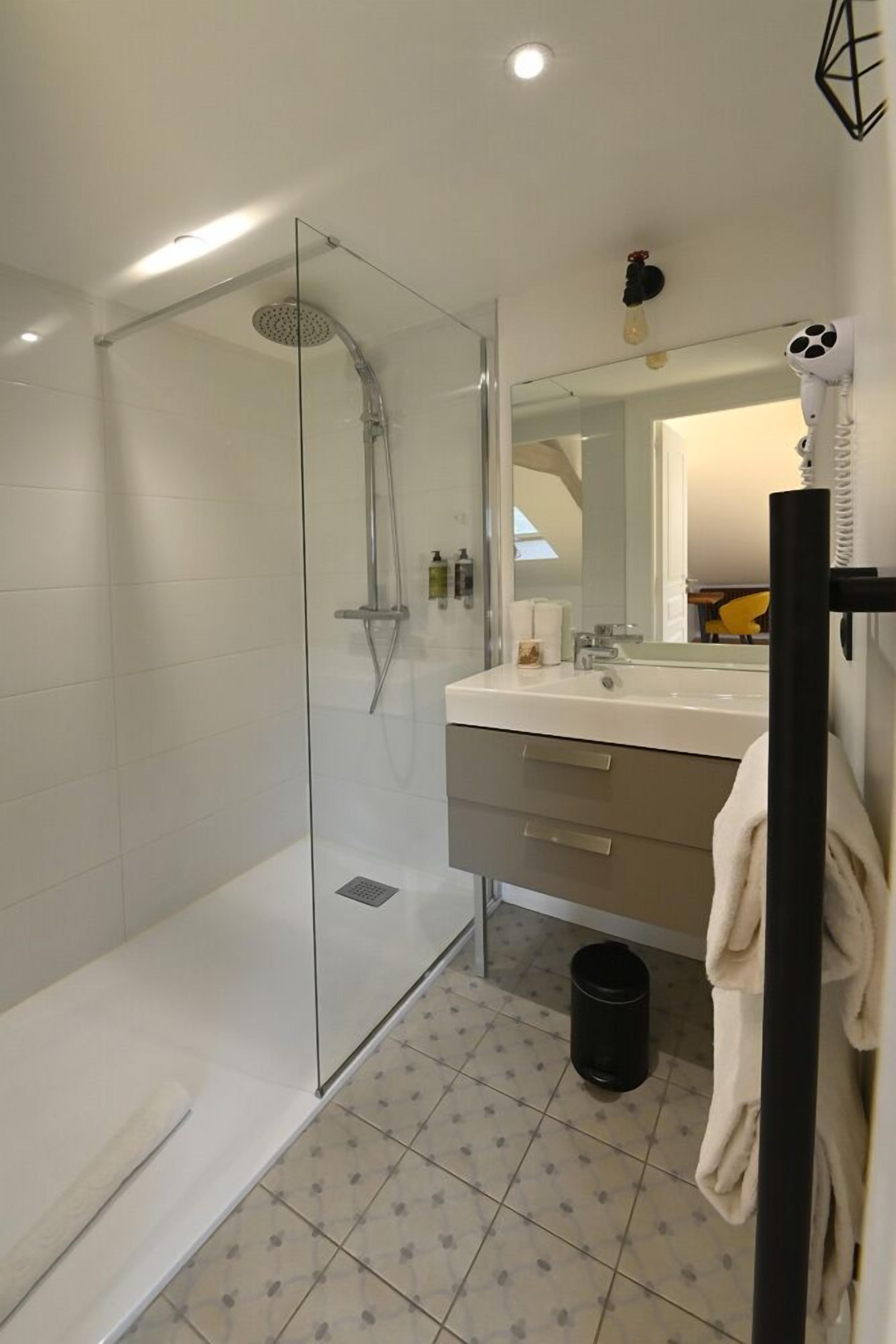 Une salle de bain moderne avec une douche à parois de verre, un lavabo blanc et un miroir au-dessus.
