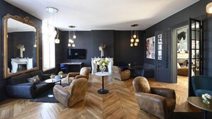 A modern living room with a herringbone floor, leather armchairs, a round coffee table, and a large mirror. - Manoir de l'évêché et Spa (Lisieux)