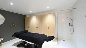 A modern bedroom with a bed, a bedside table, a small round mirror, and a wardrobe.