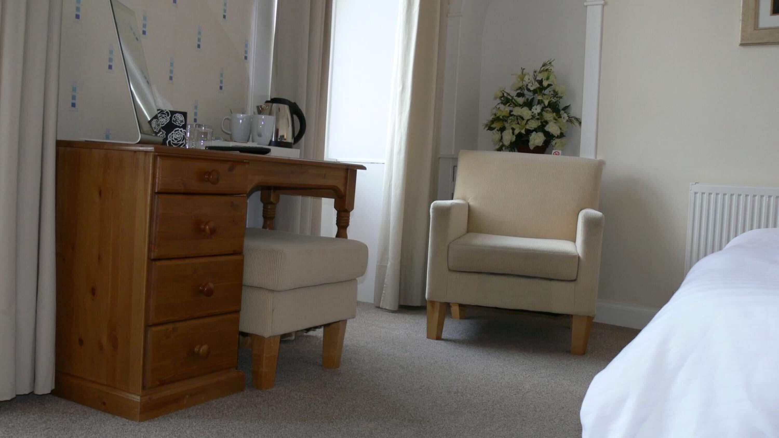 Une chambre avec un bureau en bois, une chaise, un lit et un radiateur.