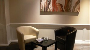 A room with two chairs, a small table, and a large abstract painting on the wall. - The Home Arms Guesthouse (Eyemouth)