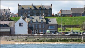 A coastal building with multiple windows and a prominent entrance. - The Home Arms Guesthouse (Eyemouth)
