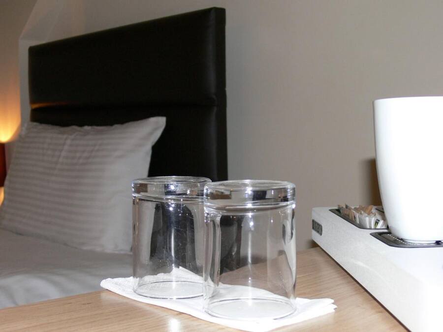 A hotel room with a bed, a bedside table, and a lamp.