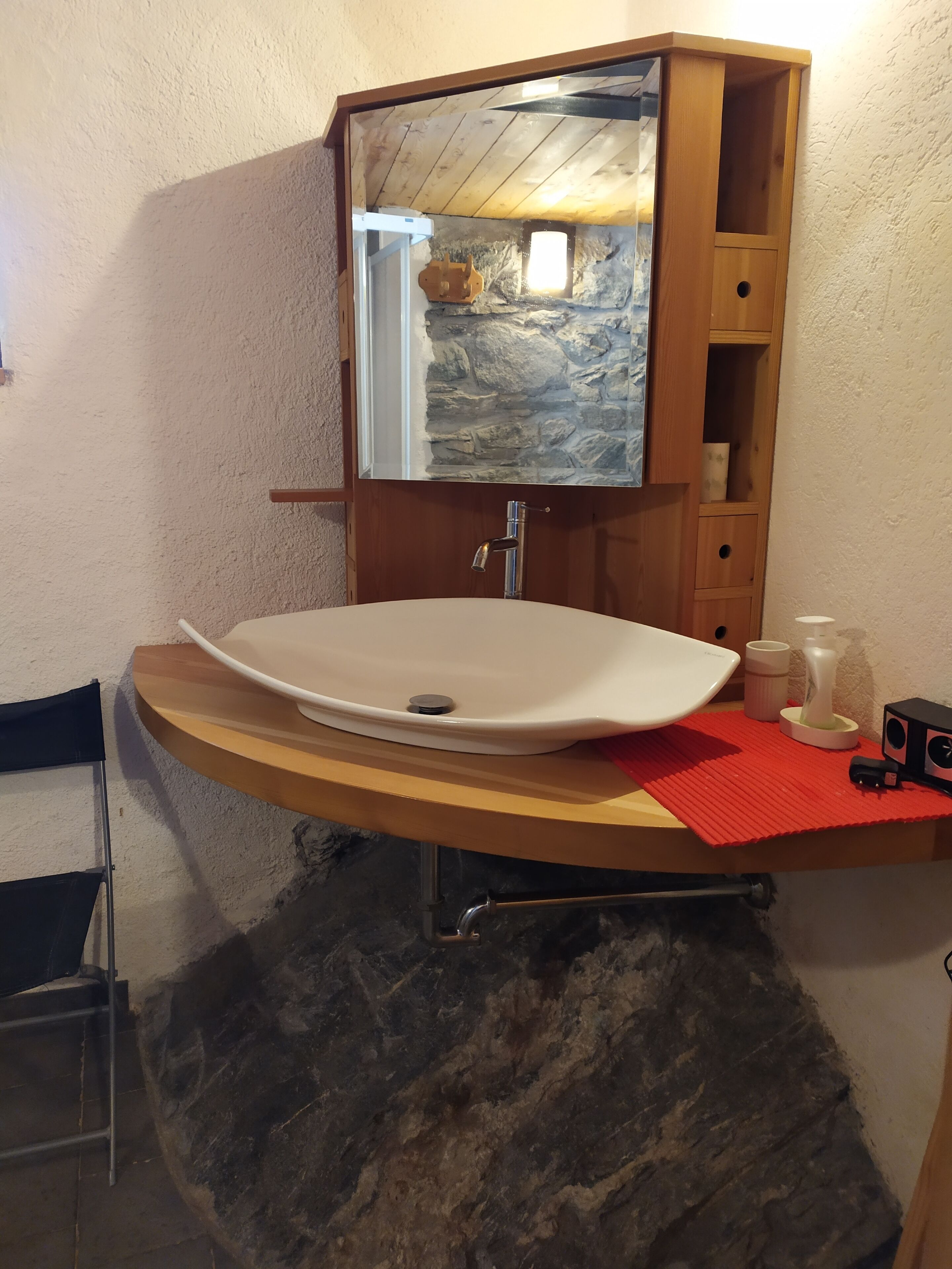 A bathroom with a stone sink, wooden vanity, and a mirror.