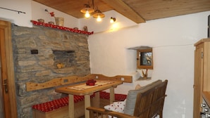 Una habitación acogedora con chimenea de piedra, muebles de madera y un ventanal pequeño.