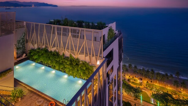 A rooftop pool with a view of the sea at dusk.