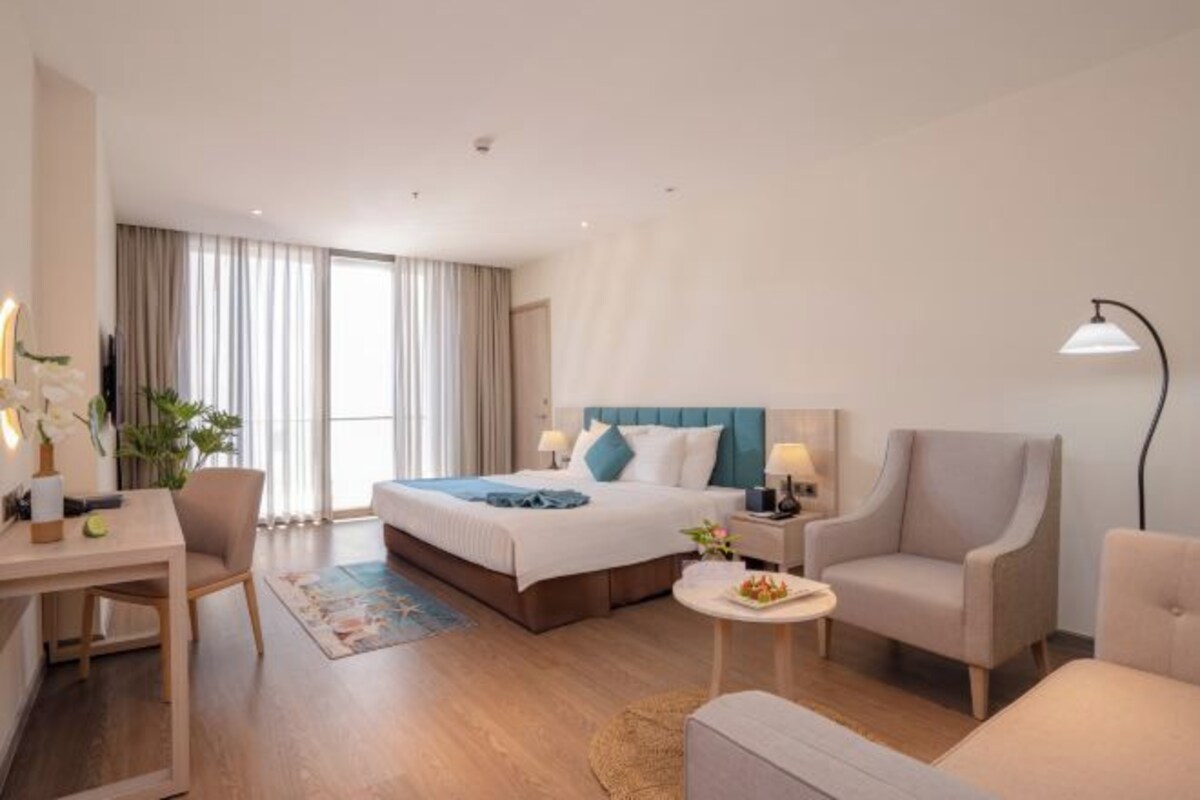 Una habitación de hotel con una cama, dos sillones, un escritorio y una mesita de noche.