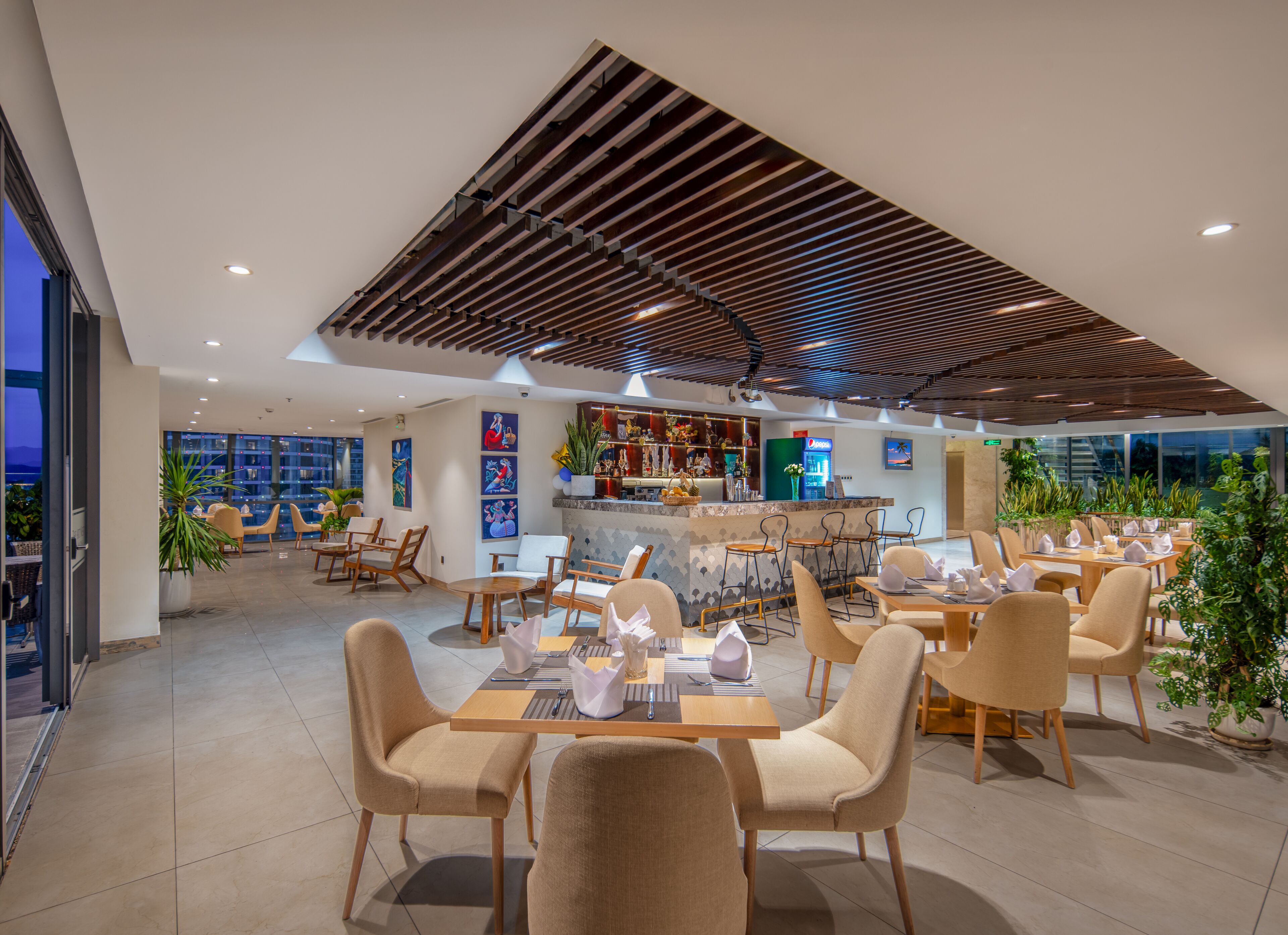 Un restaurante moderno con barra, disposición de mesas y vistas a la ciudad.