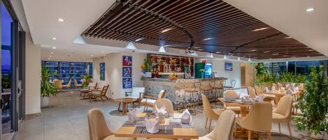 Un ristorante moderno con area bar, posti a sedere e vista sulla città.