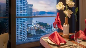 A dining table with a view of a cityscape through a large window. - Art Nest Hotel Nha Trang (Nha Trang)