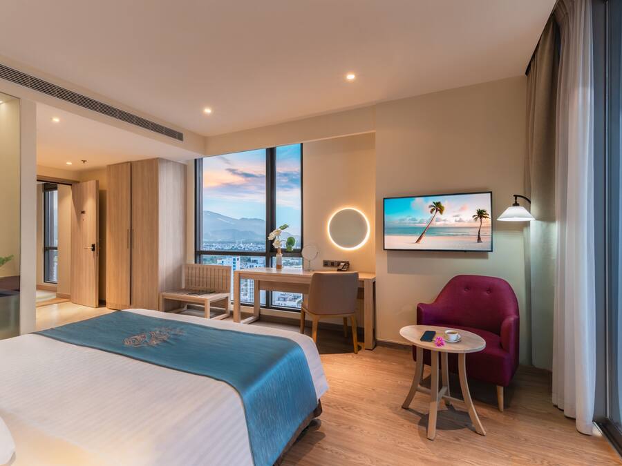 Habitación de hotel con cama, escritorio, silla y vistas de la ciudad.
