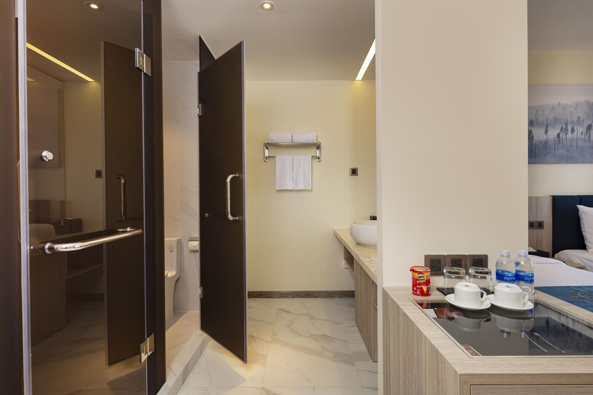 A modern bathroom with a glass shower enclosure, a toilet, and a sink area with a towel rack.