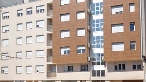 Un edificio moderno de varios pisos con una variedad de estilos de ventanas y un eje de ascensor de vidrio central.