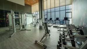 A gym with various exercise equipment, large windows, and a view of the city. - Shendo Vinhomes Metropolis (Hanoi)