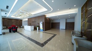 A modern hotel lobby with a reception desk, seating area, and a decorative plant. - Shendo Vinhomes Metropolis (Hanoi)