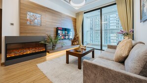 A modern living room with a fireplace, a sofa, a coffee table, and a large window offering a city view. - Shendo Vinhomes Metropolis (Hanoi)