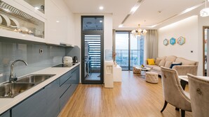 A modern kitchen with a built-in sink, a water dispenser, and a view of the city through a large window. - Shendo Vinhomes Metropolis (Hanoi)
