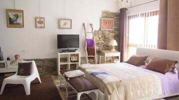 A bedroom with a bed, a television, a small table, and a chair.