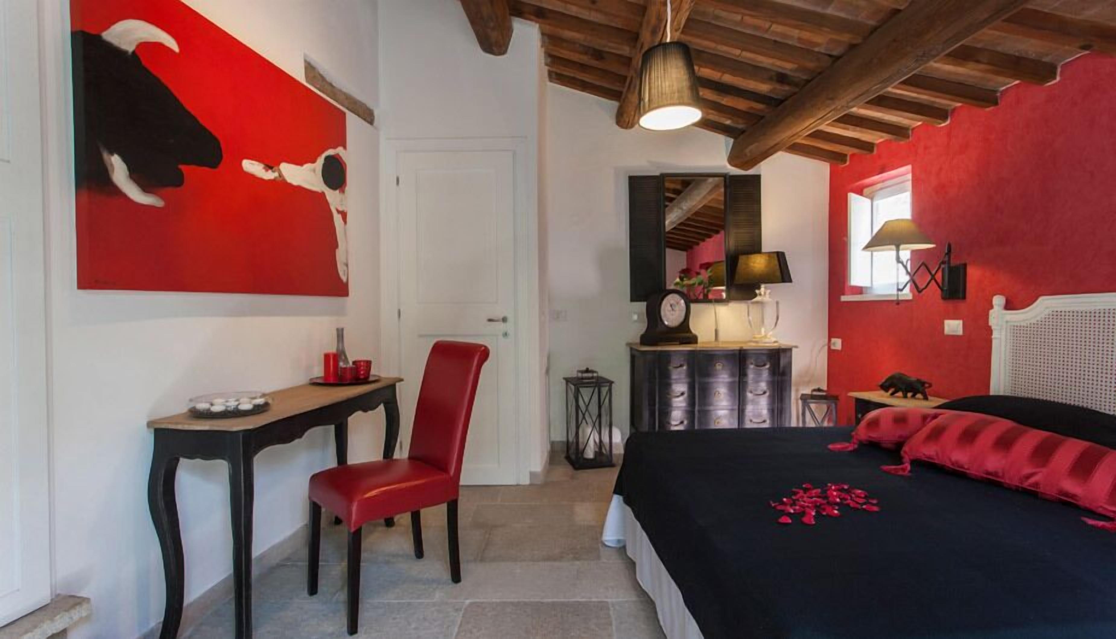 A bedroom with a bed, a desk, a chair, a dresser, and a red abstract painting on the wall.