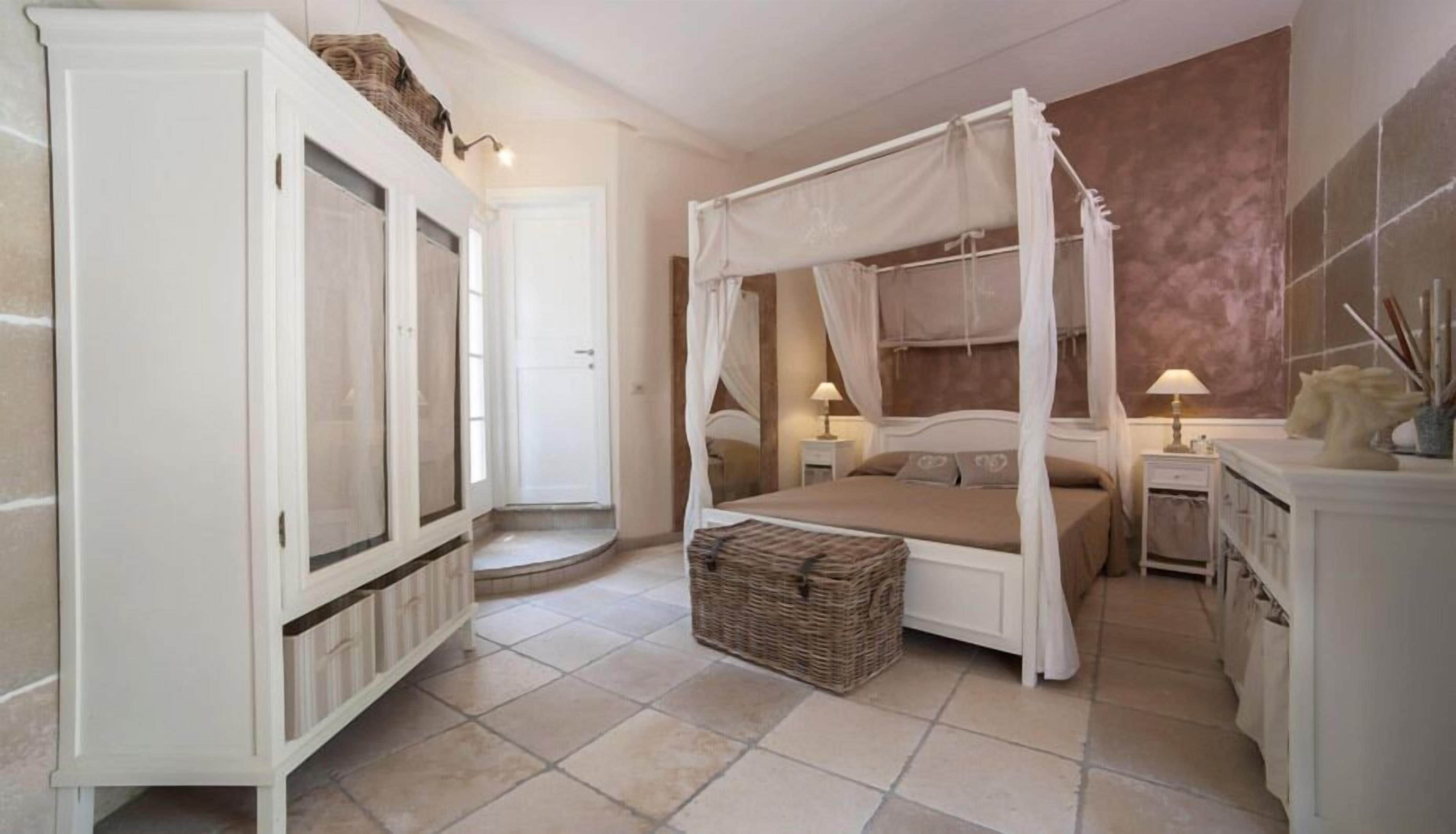 Une chambre à coucher avec un lit à baldaquin, une armoire, une table de chevet avec une lampe et un élément décoratif sur la commode.