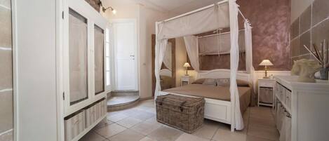 Une chambre à coucher avec un lit à baldaquin, une armoire, une table de chevet avec une lampe et un élément décoratif sur la commode.