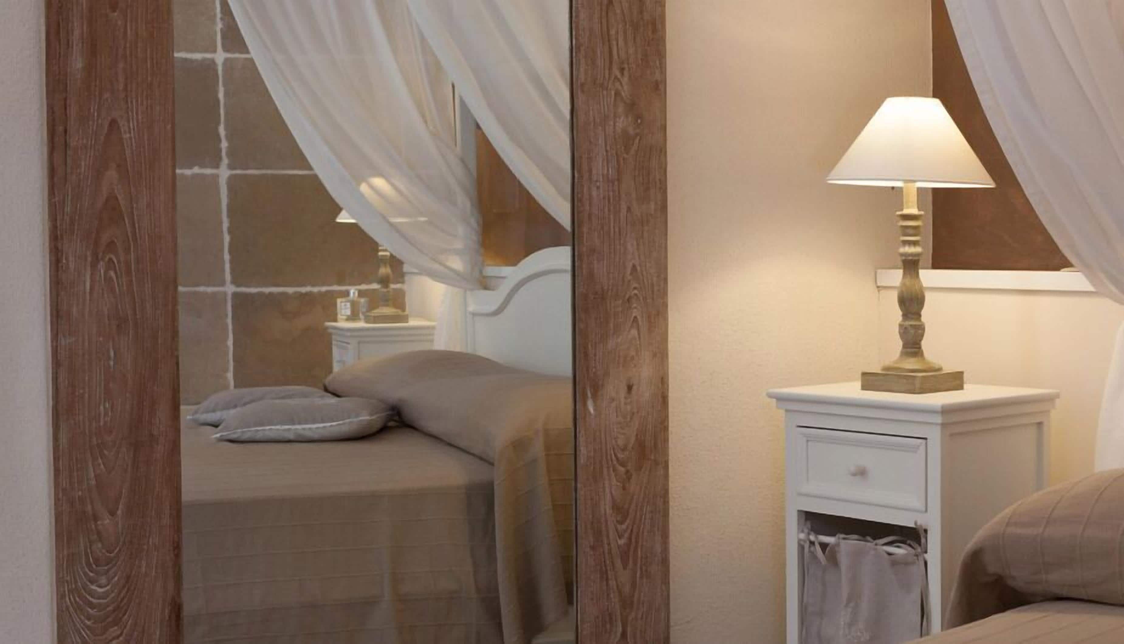 Une chambre à coucher avec un lit, une table de chevet, une lampe et un miroir.