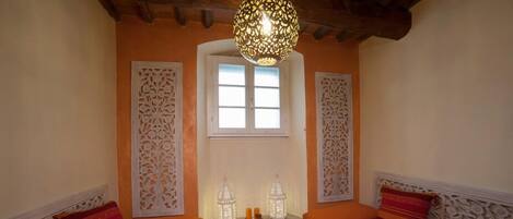 Une chambre avec deux lits, une fenêtre décorative et un luminaire suspendu.