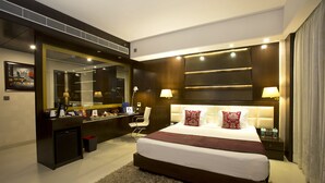 A modern hotel room with a large bed, a desk with a mirror, and a small seating area. - Kings Forth Hotels (New Delhi)