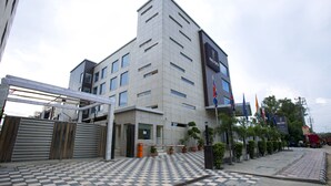 A modern building with a checkered entrance, a gated driveway, and several potted plants. - Kings Forth Hotels (New Delhi)