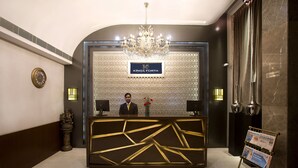 A reception desk with a chandelier, a clock, and a sign that reads "Kings Forth". - Kings Forth Hotels (New Delhi)