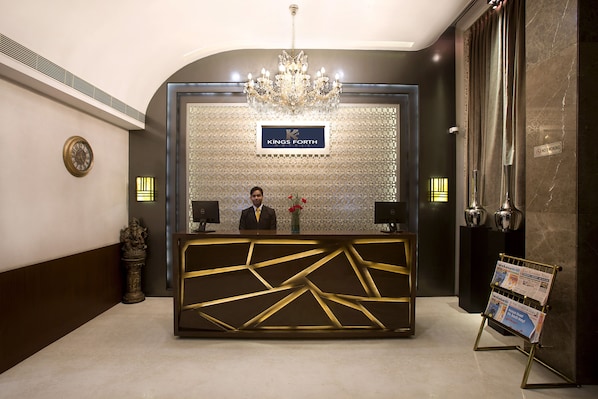 A reception desk with a chandelier, a clock, and a sign that reads "Kings Forth".