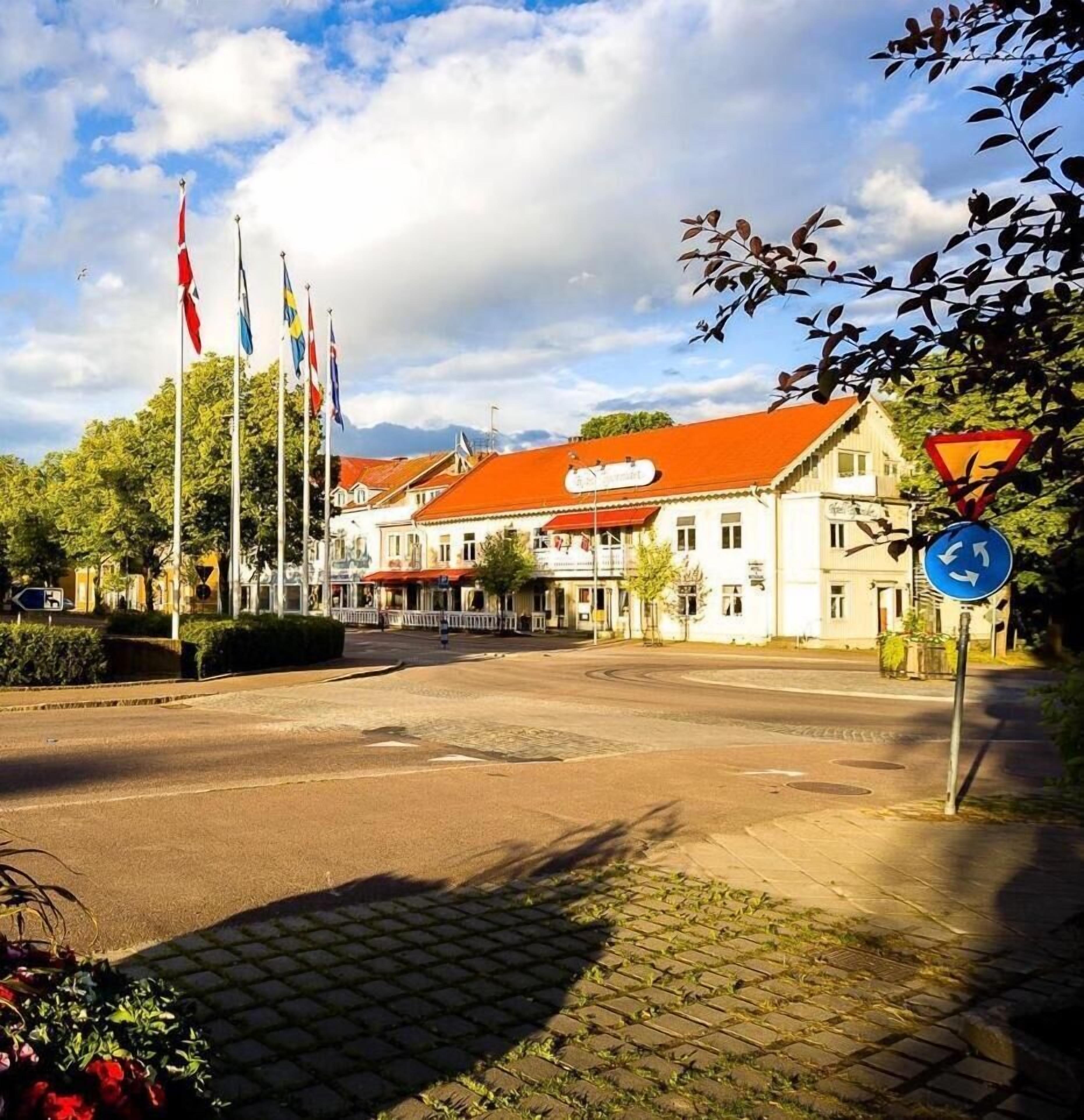 A street with buildings, flags, and a blue directional sign.