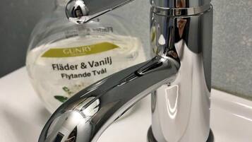 A chrome faucet with a soap dispenser on a white sink.