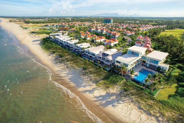 A coastal resort with beachfront villas, a swimming pool, and a view of the ocean.