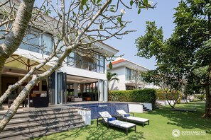 A modern house with a pool, outdoor seating, and a well-maintained garden.