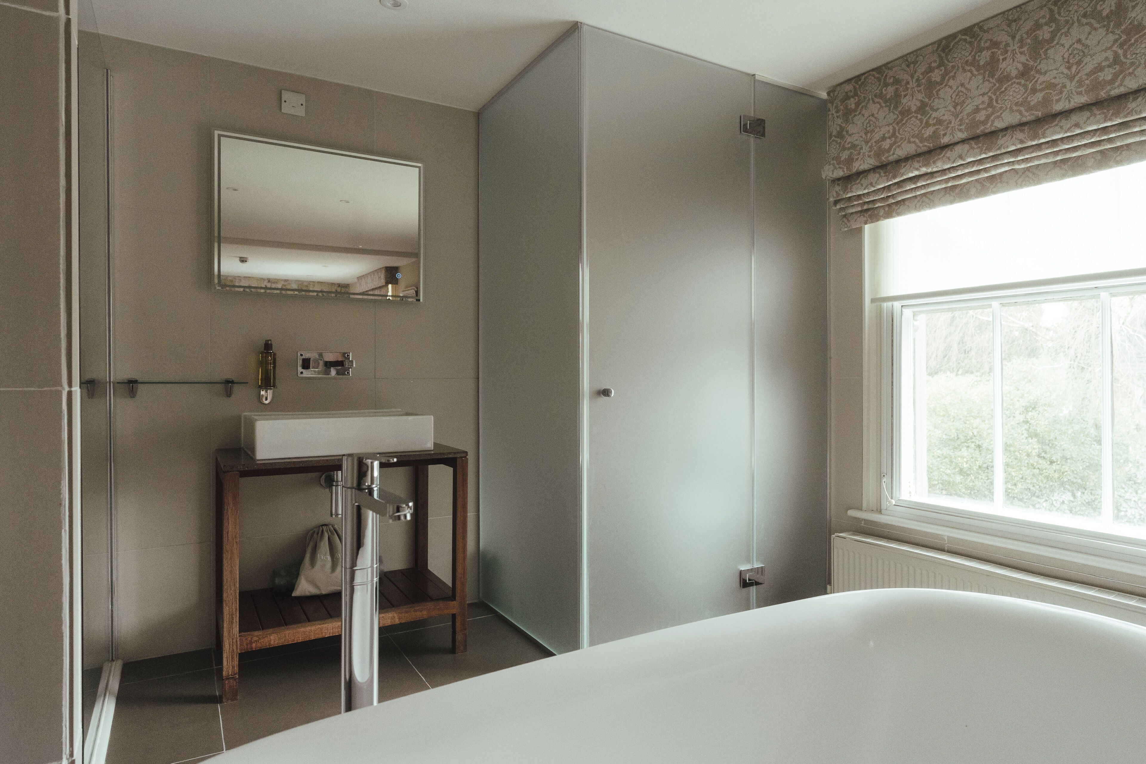 A bathroom with a bathtub, a sink, a mirror, and a shower.