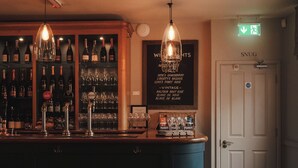 A bar area with a counter, hanging lights, and a wall with wine bottles and glasses. - Winemaker's Pub (Cranbrook)