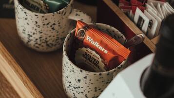 Dos tazas de cerámica con motas sobre una superficie de madera, cada una con una barra de chocolate Walkers.