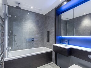 A modern bathroom with a glass-enclosed shower, a standalone bathtub, and a vanity with a blue-lit mirror. - 2 Bed Property Close to Heathrow Airport (Brentford)