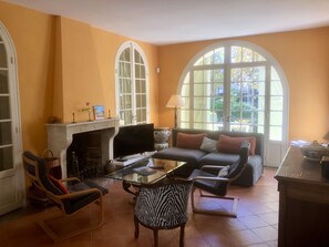 A living room with a fireplace, a sofa, a glass coffee table, and a zebra-patterned chair. - Villa in an enclosed 3608 sq ft garden planted with trees (La Ciotat)