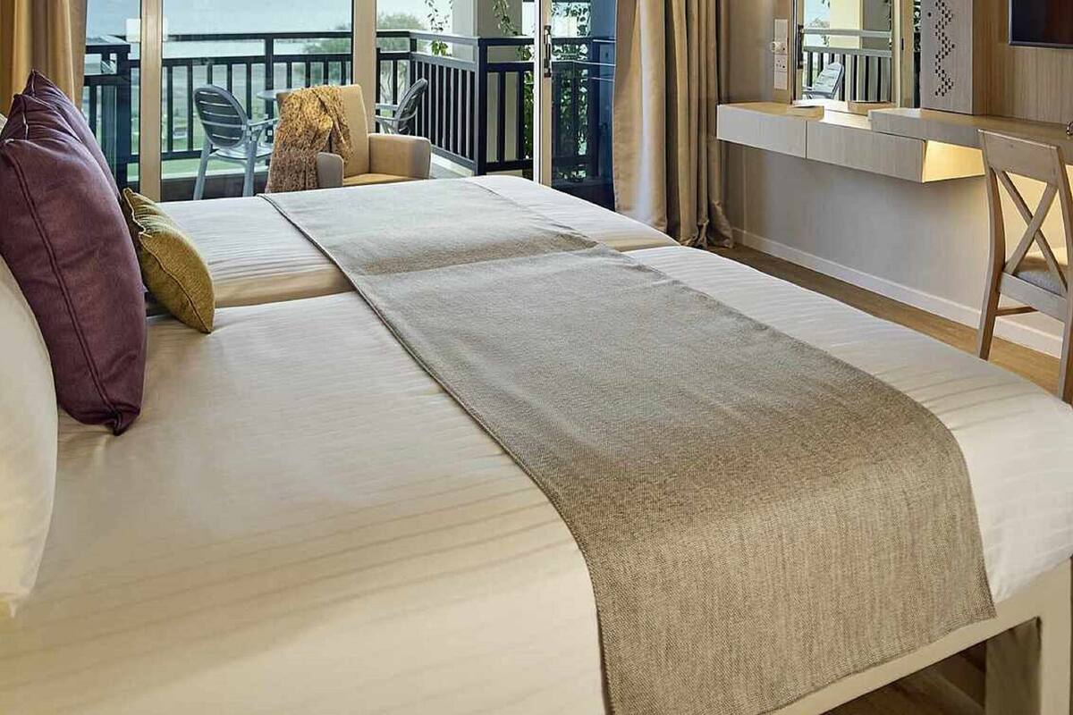 A hotel room with a large bed, a desk, and a view of the outdoors.