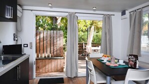 A modern kitchen with a dining area, wooden deck, and outdoor seating. - Camping Village I Tre Moschettieri (Comacchio)