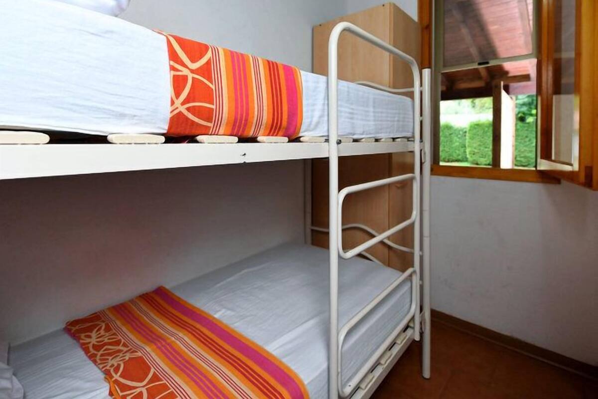 A bunk bed room with a window and a wooden cabinet.