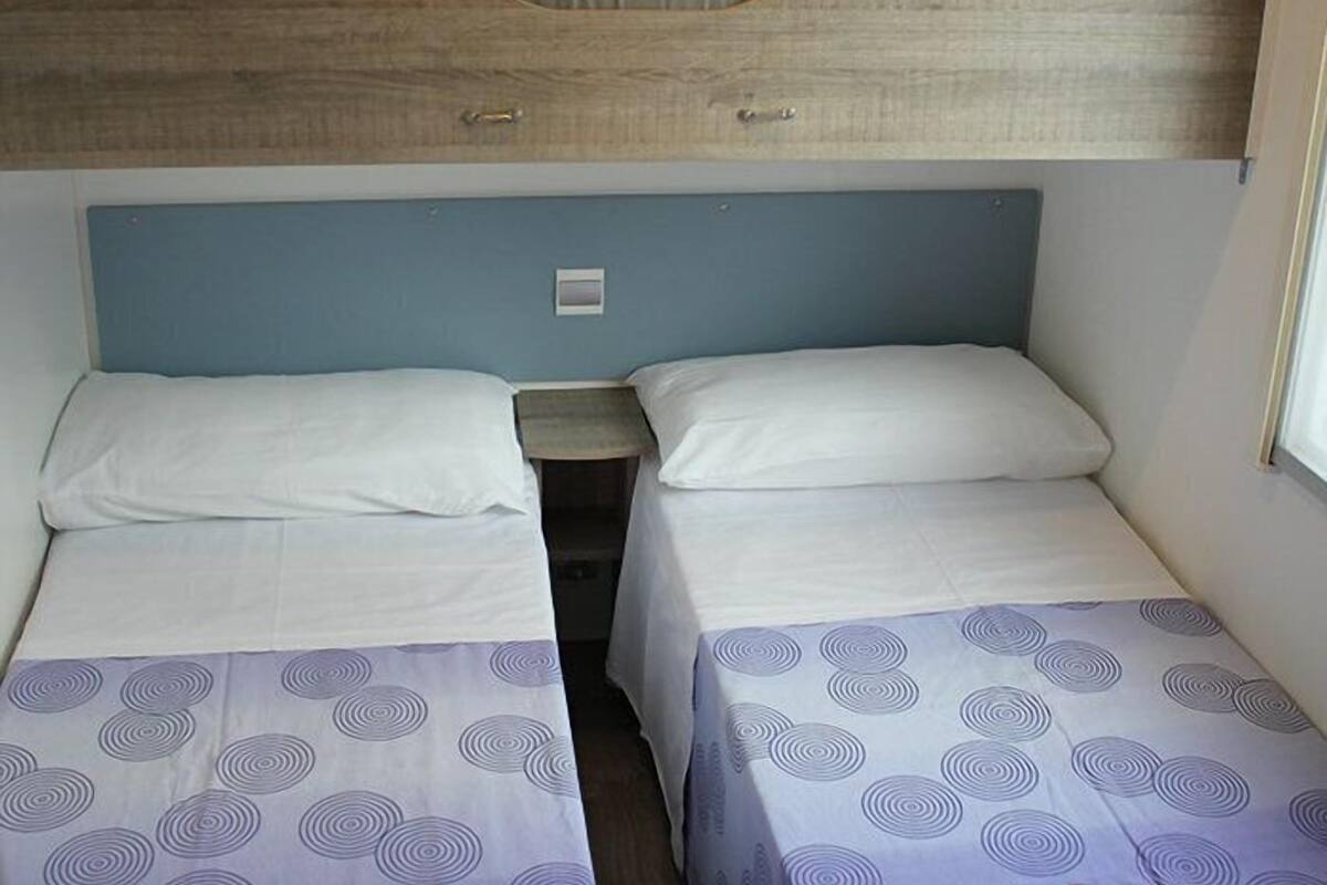 A bunk bed room with two beds, a small table, and a headboard.