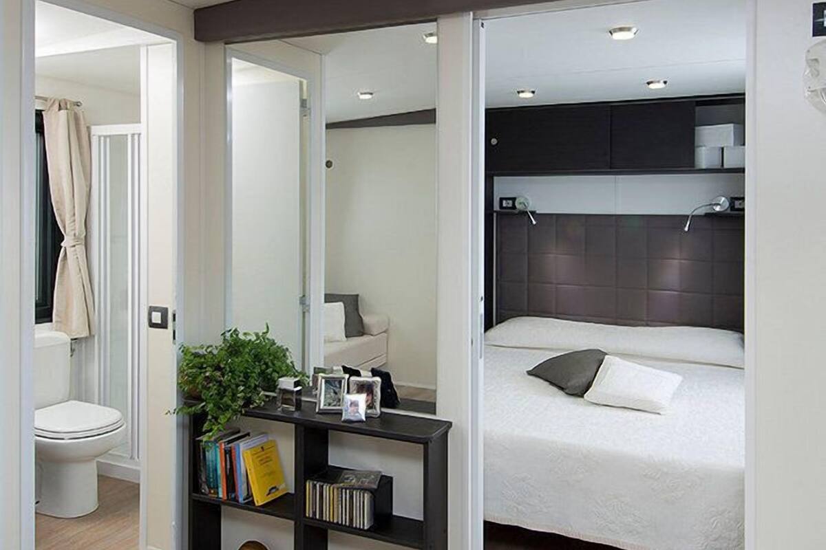 A modern bedroom with a bed, bedside table, and a bookshelf.