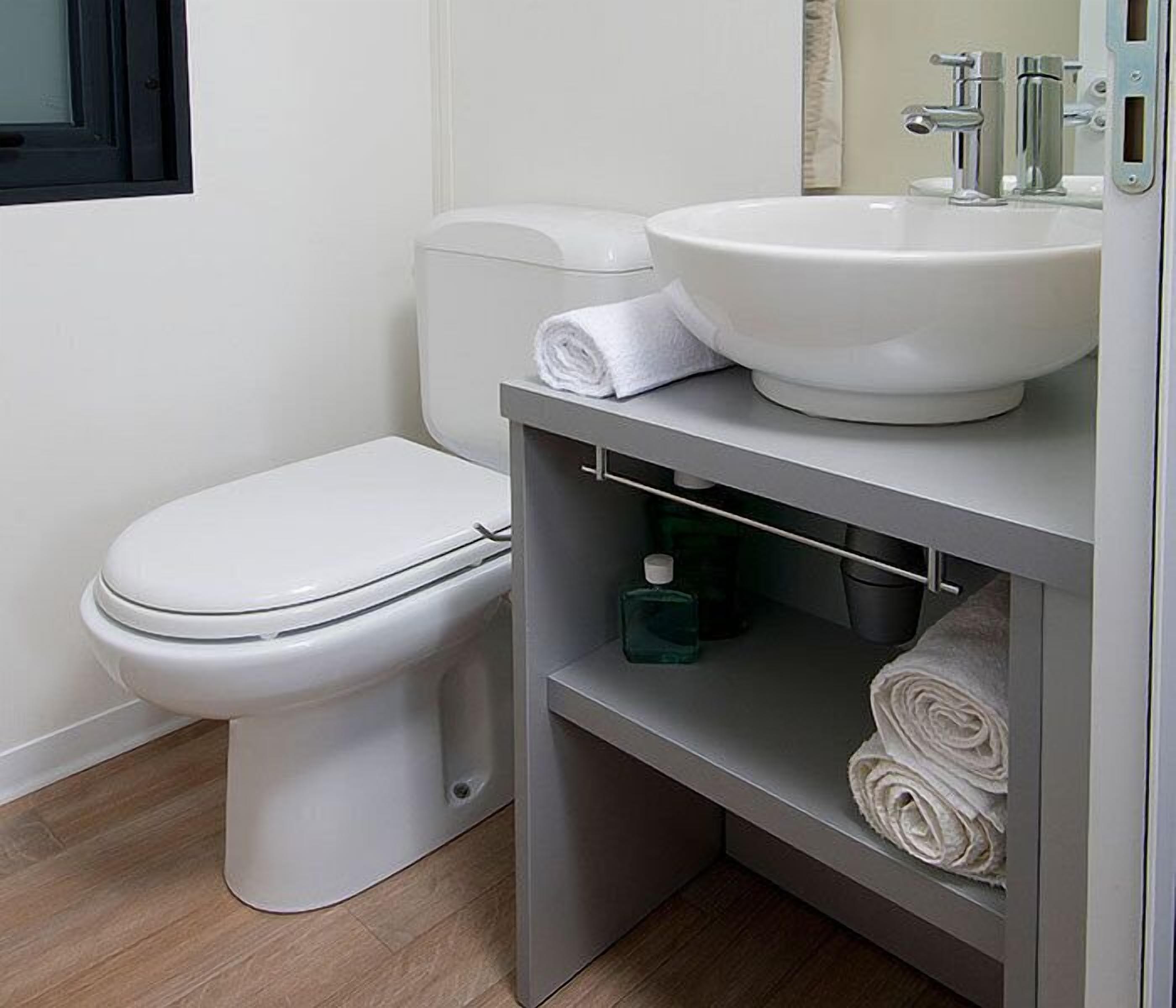 Un baño moderno con inodoro y lavamanos blancos, y un perchero para toallas.